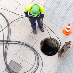 Engineer working on subsurface electrical utilities through manhole