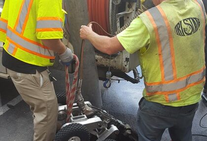 engineers introducing inspection robot in a manhole
