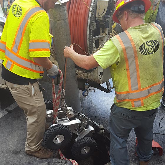 engineers introducing inspection robot in a manhole